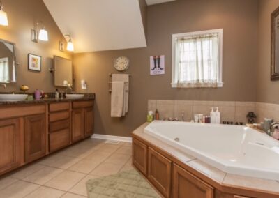 Modern bathroom with wooden cabinetry, corner bathtub, and neutral color scheme.