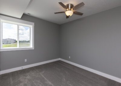 Empty room with gray walls, a window, and a ceiling fan.