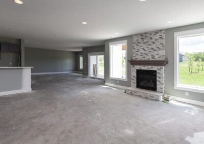 Unfurnished living room in a new house with a fireplace and a view of the outside environment through large windows.