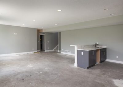 Unfinished room interior with gray walls, concrete floors, and a partially installed kitchen counter.