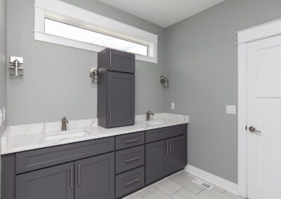 Modern bathroom with dual vanity and gray cabinetry.