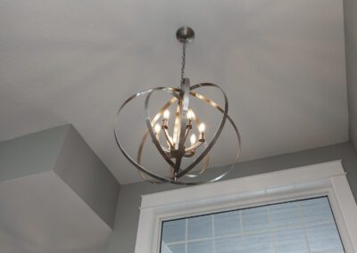 Modern spherical chandelier with multiple bulbs hanging from a ceiling in a room with a window.