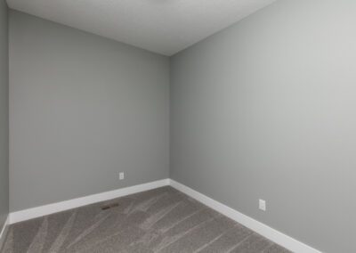 An empty room with gray walls and a carpeted floor.