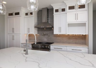 Modern kitchen interior with white countertops, stainless steel appliances, and gray backsplash tiles.