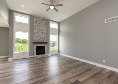 A spacious room with high ceilings featuring a fireplace and tall windows with a view of the outdoors.