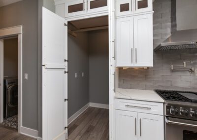 Modern kitchen with white cabinetry and stainless steel appliances next to a laundry room with an open door.