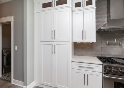 Modern kitchen interior with white cabinetry, stainless steel appliances, and gray subway tile backsplash.