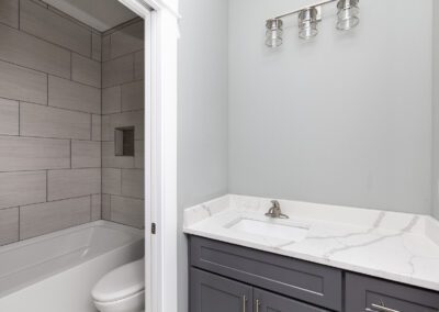 Modern bathroom interior with gray tiles and white bathtub.